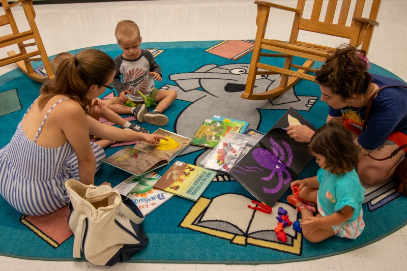 A parent reads to her children with books from a Traveling Tales Kit