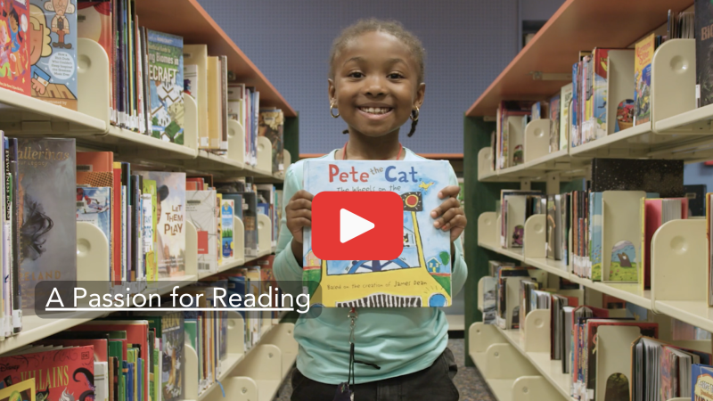 Child in library with Pete the Cat book. Click to open video.