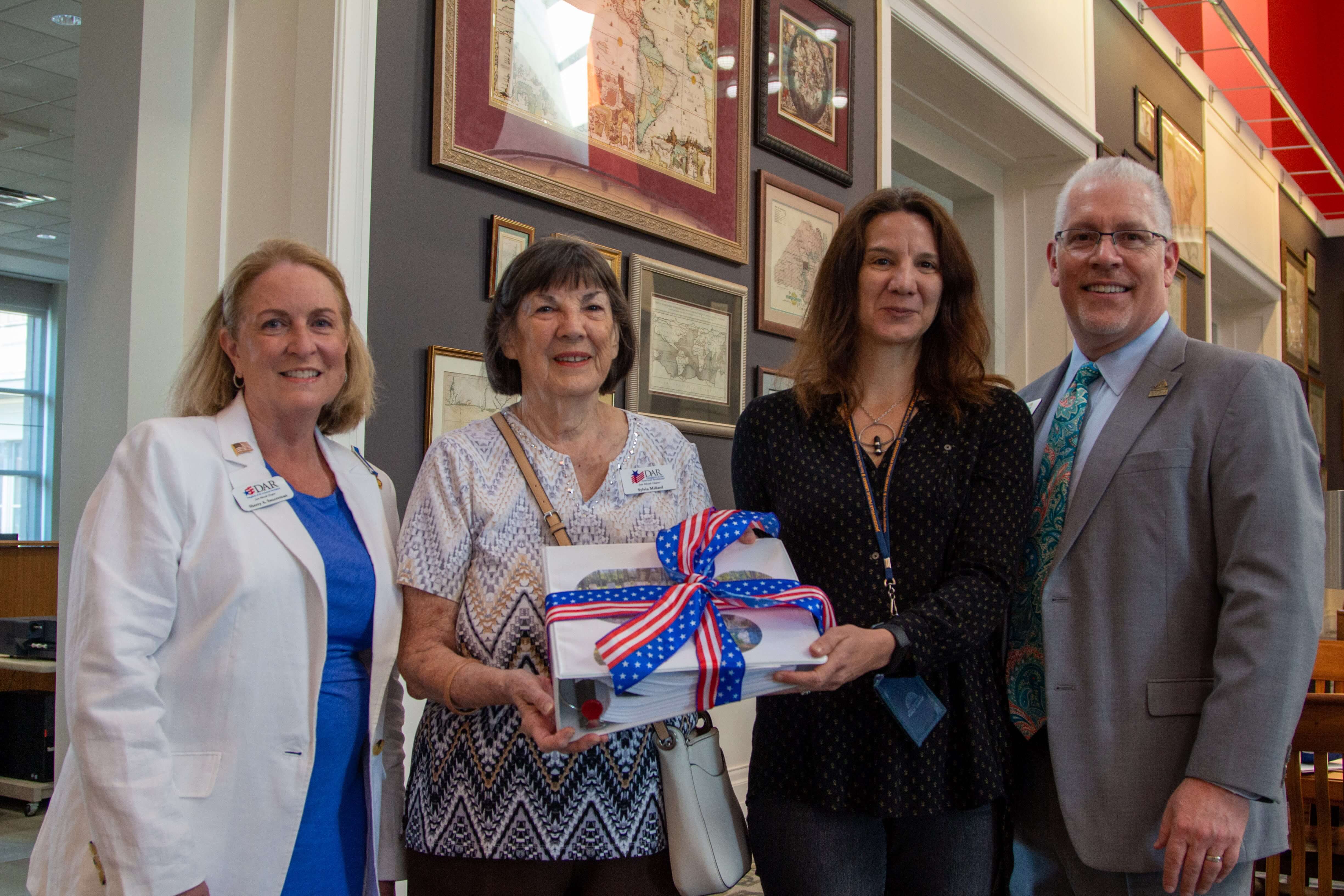 Photo of the Daughters of the American Revolution donating their Forgotten Heroes project book to library staff