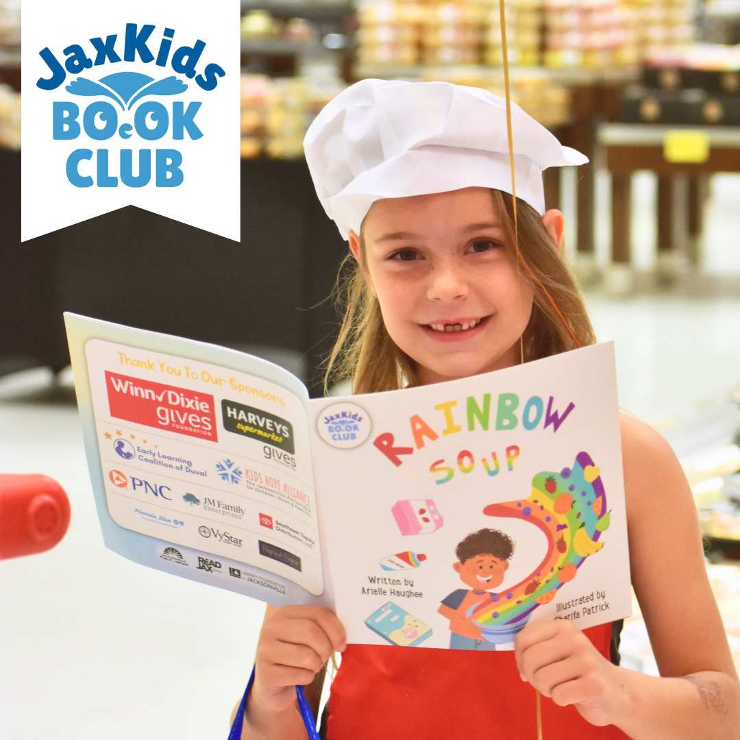 A young girl holds a book titled Rainbow Soup. The JaxKids Book Club logo hangs in the top right corner.