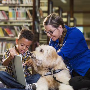 Child reading to a dog in the Library with an adult