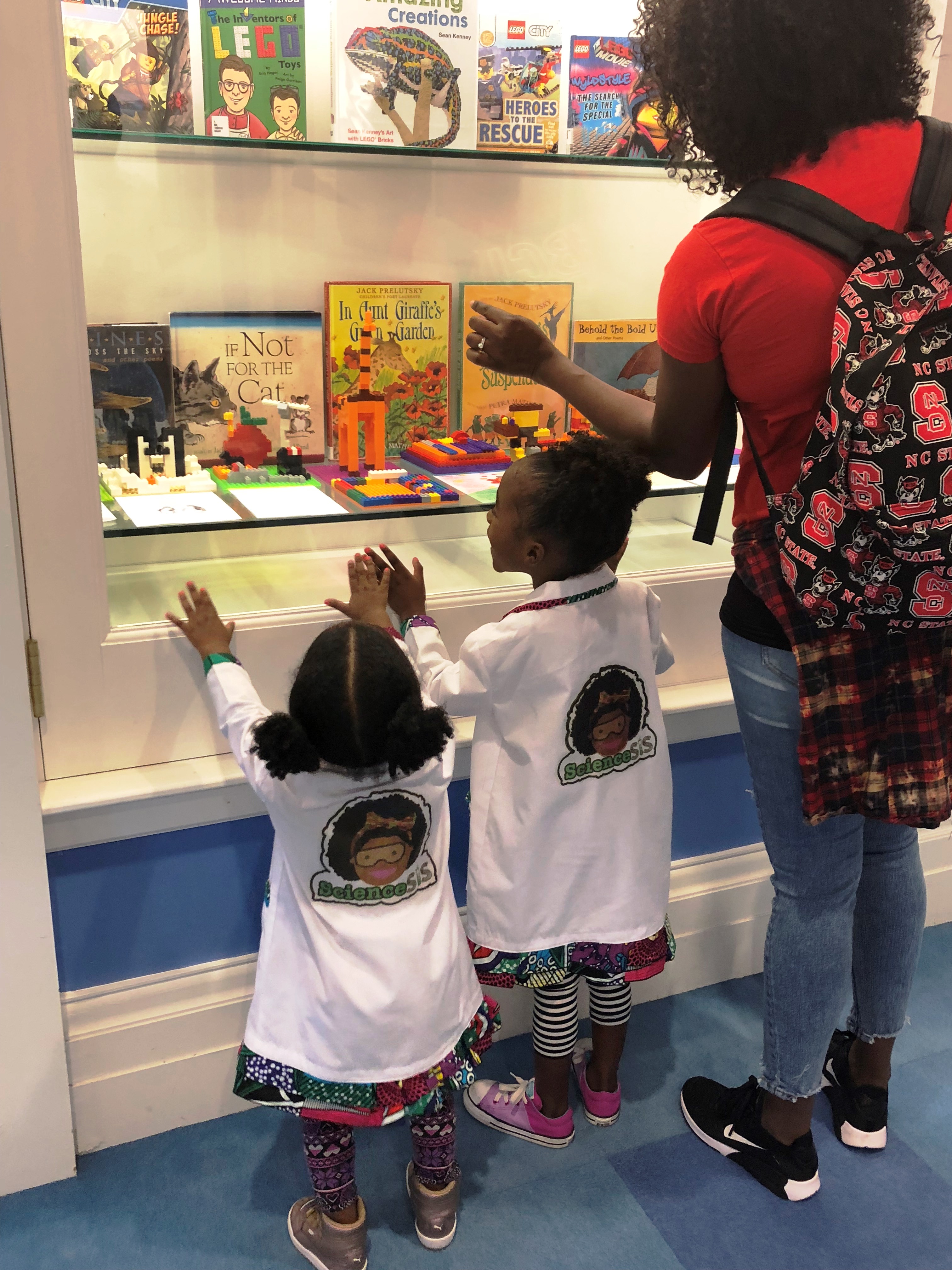 Angelina and Berkeley in their white lab coats looking into a display case at the children's department