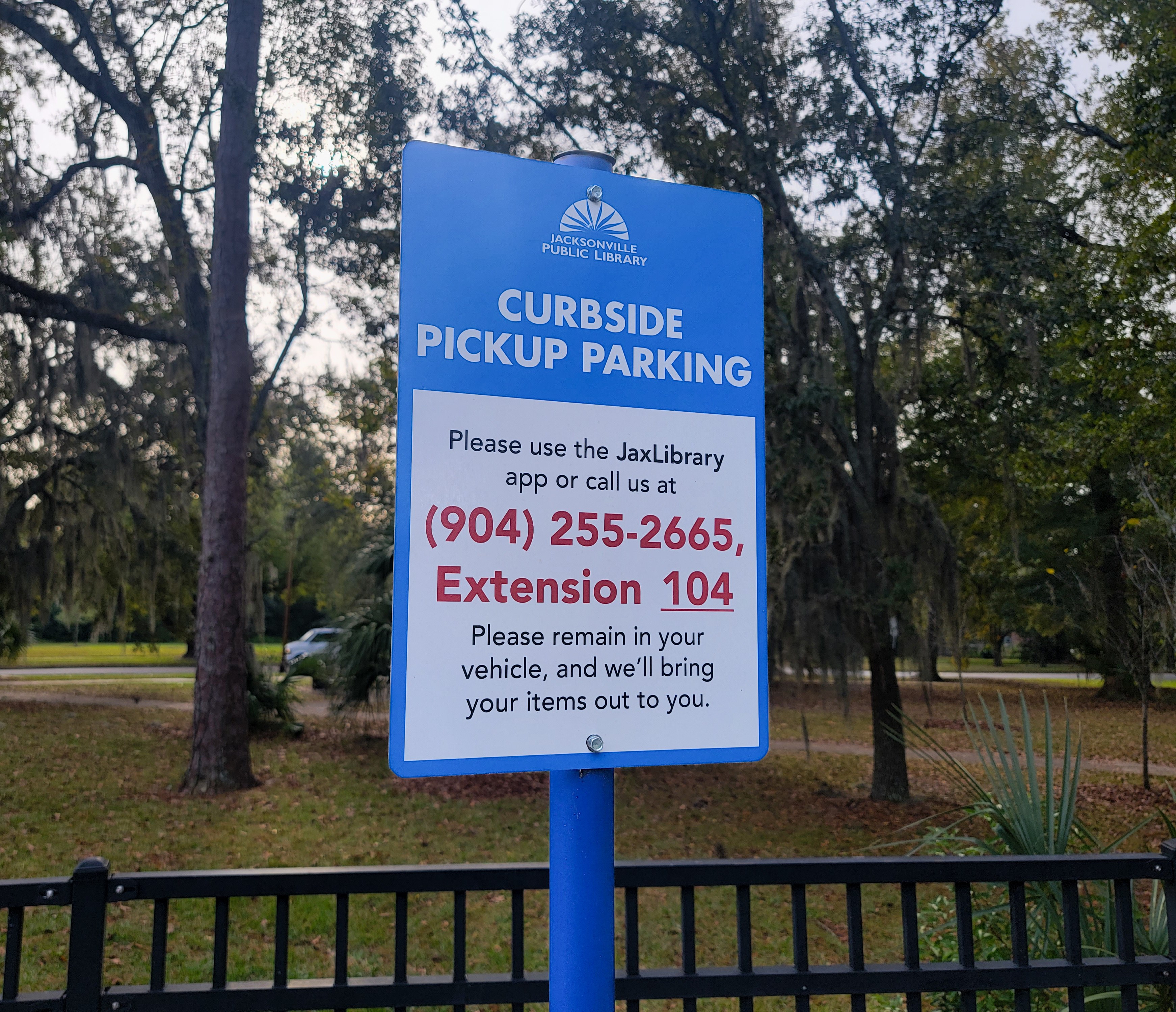 A photo of a Curbside Pickup parking sign, with instructions and a phone number