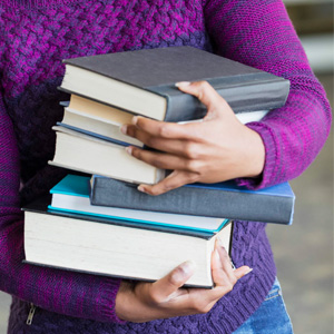 A person with a stack of new books from the Jacksonville Public Library