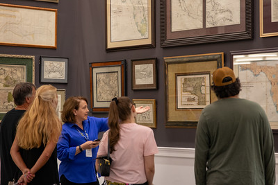 A docent raises her hand while speaking about the main library's map room