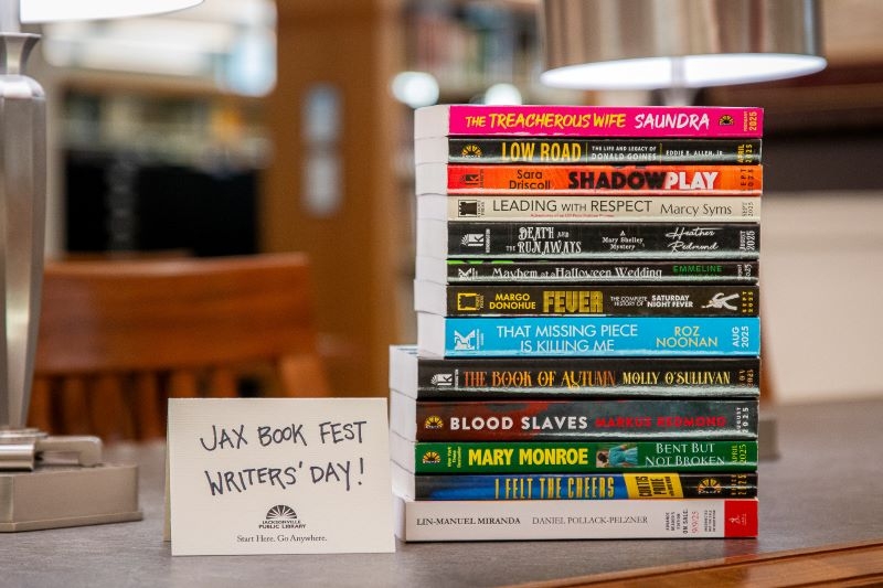 A stack of Advanced Reader Copies of books, next to a sign that reads: "Jax Book Fest Writers' Day"