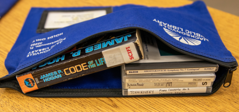 Books and CDs inside a blue reusable nylon bag