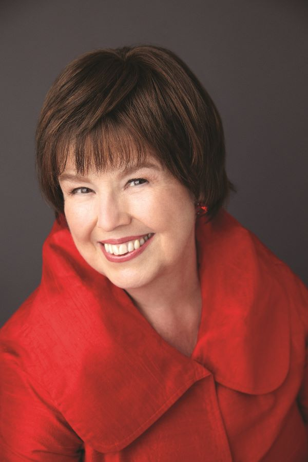 Debbie Macomber headshot by Deborah Feingold. The author is smiling and wearing a red coat.