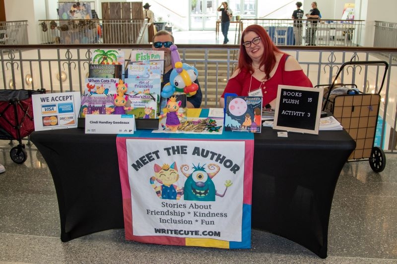 An author of children's books sits behind a table full of her books at a Jax Book Fest