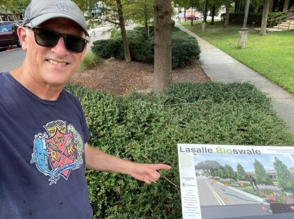 Jimmy Orth poses in front of a informational sign about the bioswale at San Marco Branch Library
