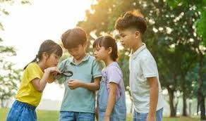 Kids looking at a magnifying glass outdoors