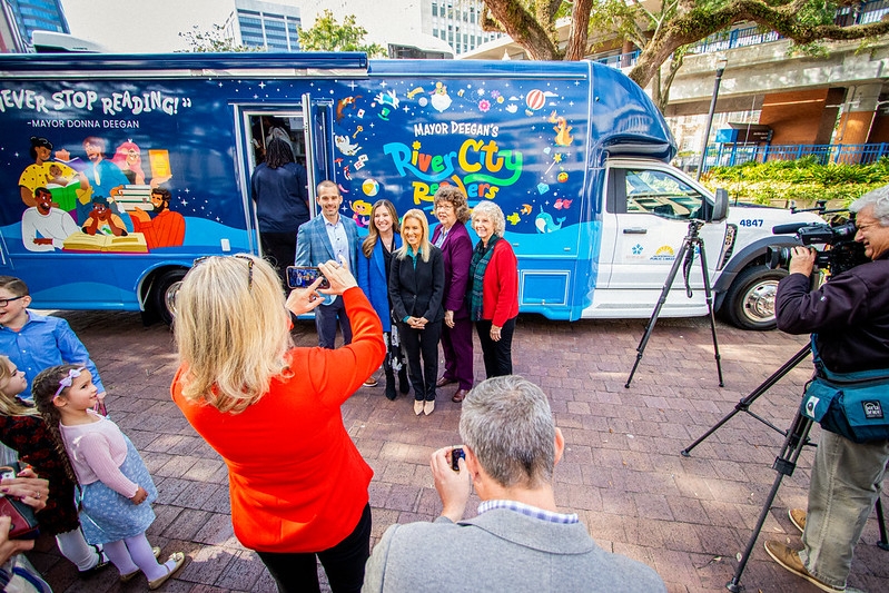 Mayor Deegan poses for a photo in front of the newly unveiled bookmobile across from City Hall in James Weldon Johnson Park