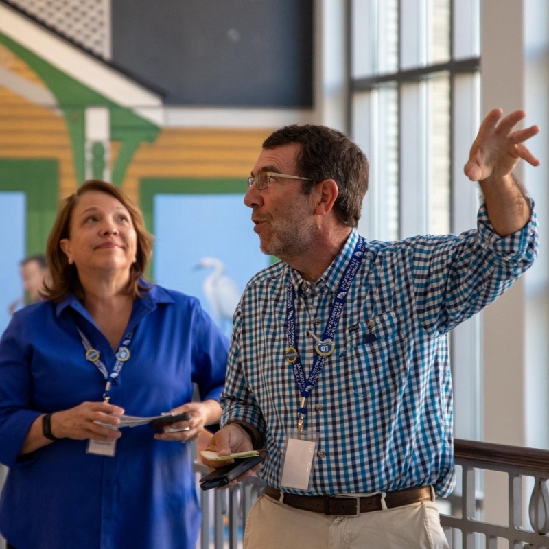 A docent raises his hand while speaking about the main library's art
