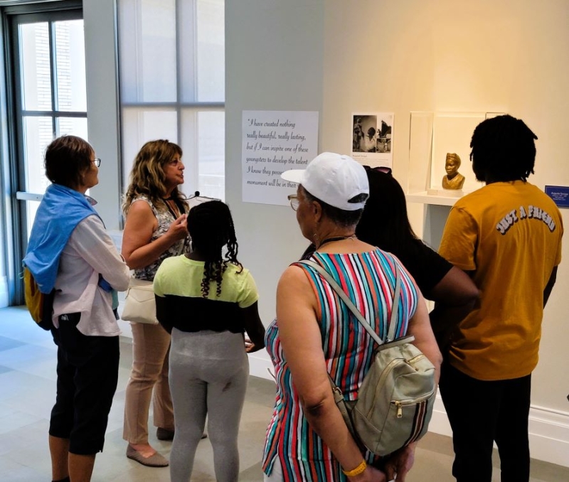 Photo of an art tour in progress. Tour guide is talking about the August Savage bust on the fourth floor.