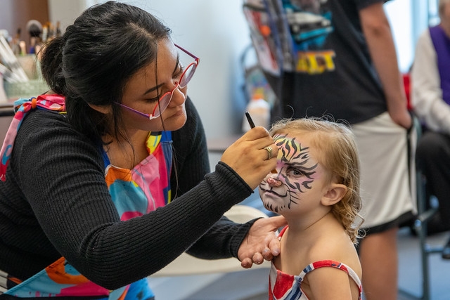 a young child's face is being painted as a tiger