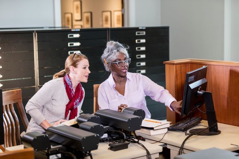 Stock photo of two women using a microfilm reader