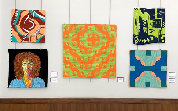 Several small to medium sized quilts on display like paintings on a wall