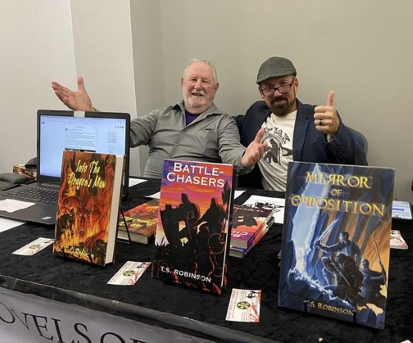 Two authors exhibiting together, with their books on the table in front of them