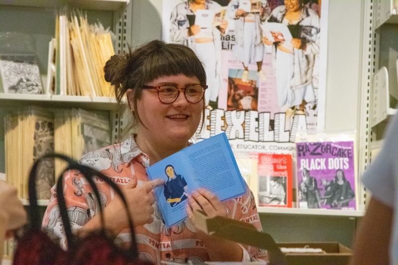 A zinester holds a zine open to show others