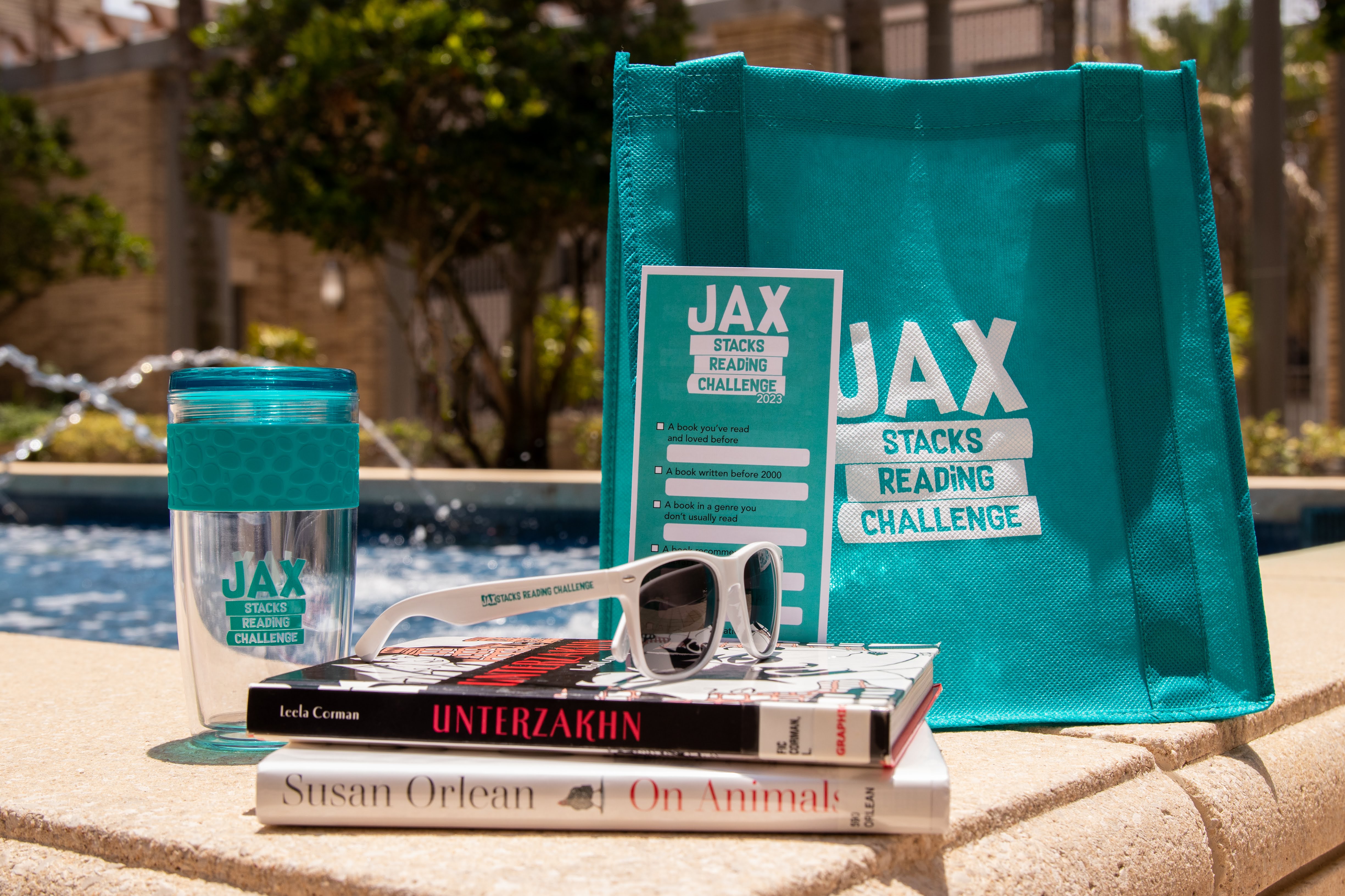 Photo of Jax Stacks tumbler and sunglasses sitting on the edge of a water fountain