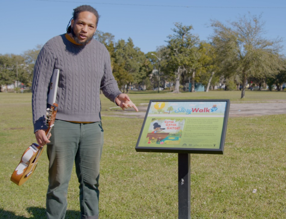 Mr. Joe standing by the mounted StoryWalk sign