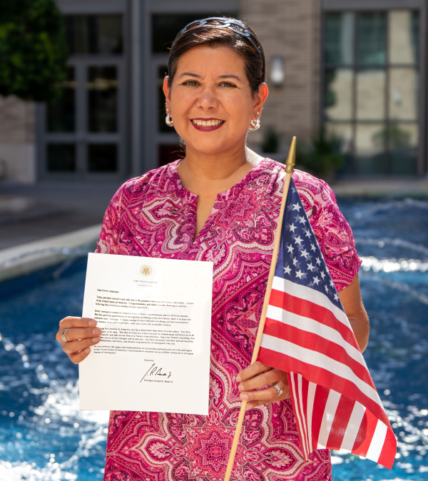 Milu Benko holding an American flag and her letter from the US citizenship and immigration services