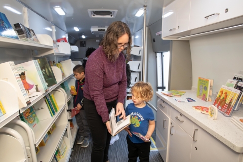 A mother and son look at a book inside the bookmobile
