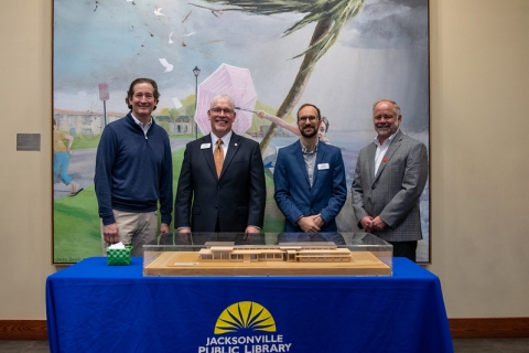 Library Director Tim Rogers and Library Supervisor Ryan Merkel pose with an architect and contractor. They stand behind the scale model of the library and community center they helped design and build.