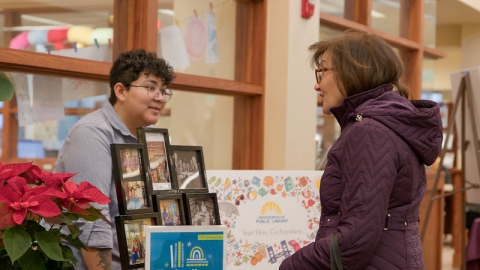 Library staff member Michelle talks to a customer about volunteer opportunities