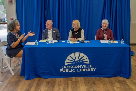 A photo of the moderator and four panelists for the Forward Thinking discussion. From left to right: Kelsi Hasden, Tracy Thompson, Robin Robinson and Dorothy K. Fletcher. They sit at a table with a blue tablecloth and the library logo in the center.