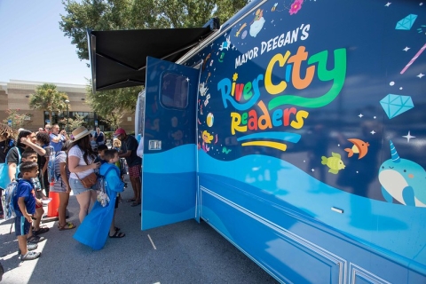 A closeup of the bookmobile, showing the logo for Mayor Deegan's River City Readers