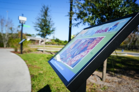 Photo of a StoryWalk panel near the Emerald Trail sign