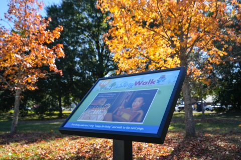 Photo of StoryWalk panel with trees in the background