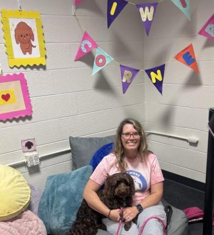 A photo of smiling Library volunteer with her therapy dog.