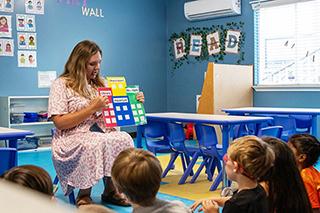 woman reads to a book to children in a classroom