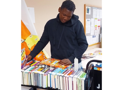 Teen volunteer prepares to shelve books at library