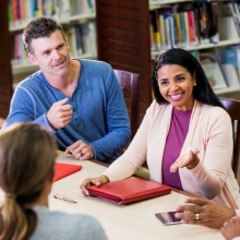 Woman leading a group of professionals in a meeting in the library