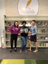 Jenna and Hurley posing with Nikesha Williams in front of the local author collection