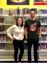Badr Milligan of the shortbox podcast with Jenna of the Completely Booked podcast in front of the comic book collection at the Jacksonville Public Library