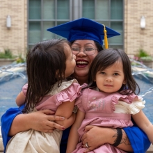 Abigail in a graduation cap and gown, hugging with her kids