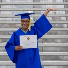 Nicole Mitchell in cap and gown holding her diploma