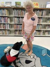Library volunteer Beckie smiles while gazing at her therapy dog Stormy.